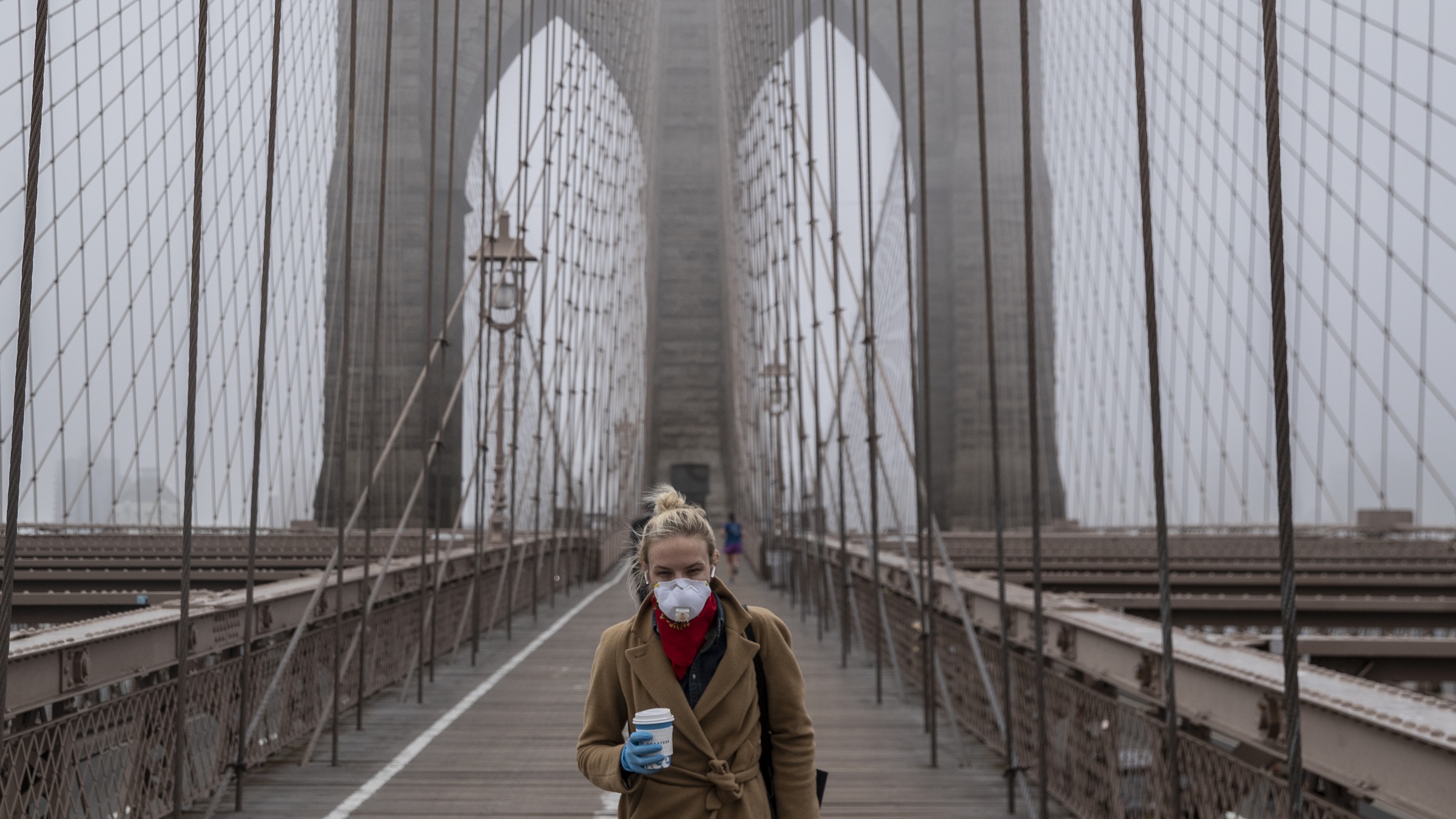 A woman wearing a face mask crosses the Brooklyn Bridge, New York
