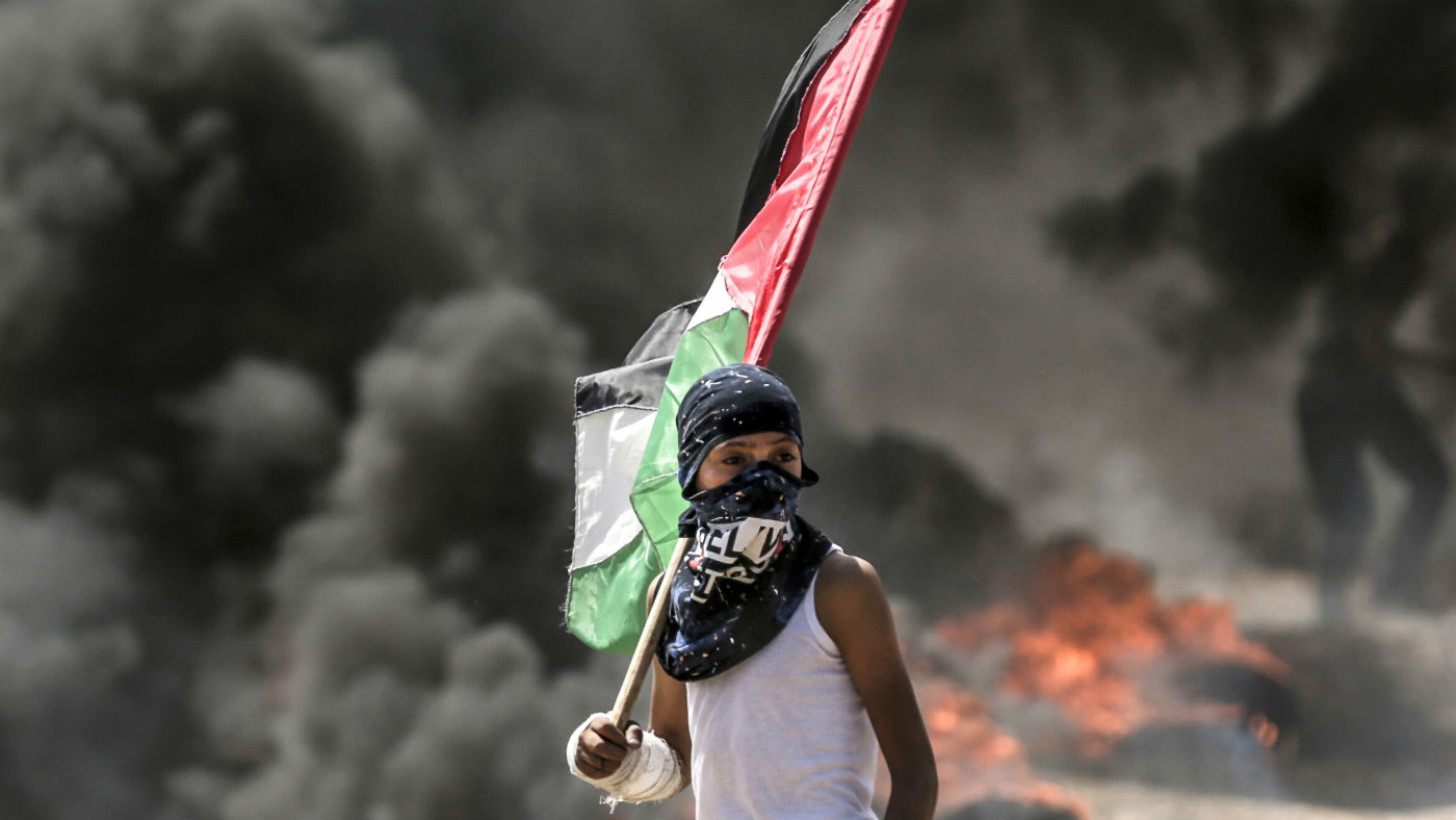A Palestinian boy holds his national flag during clashes with Israeli security forces near the Gaza border