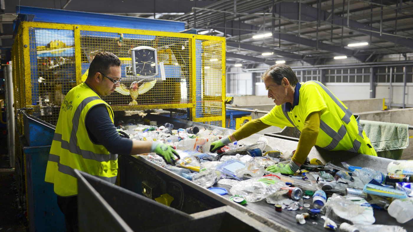 Workers sort recycling on conveyor belt