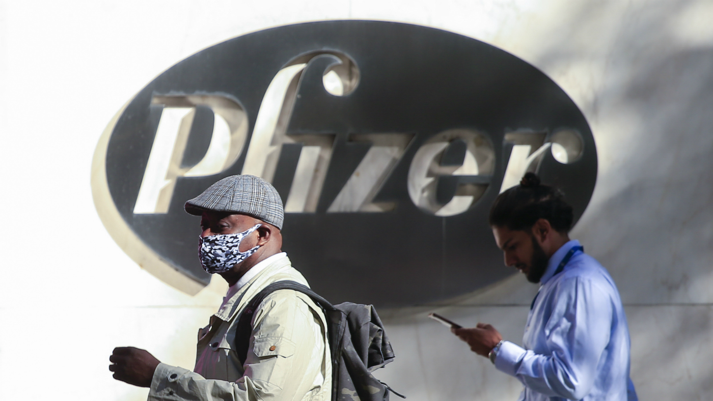A man in a face mask walks past the Pfizer headquarters in New York